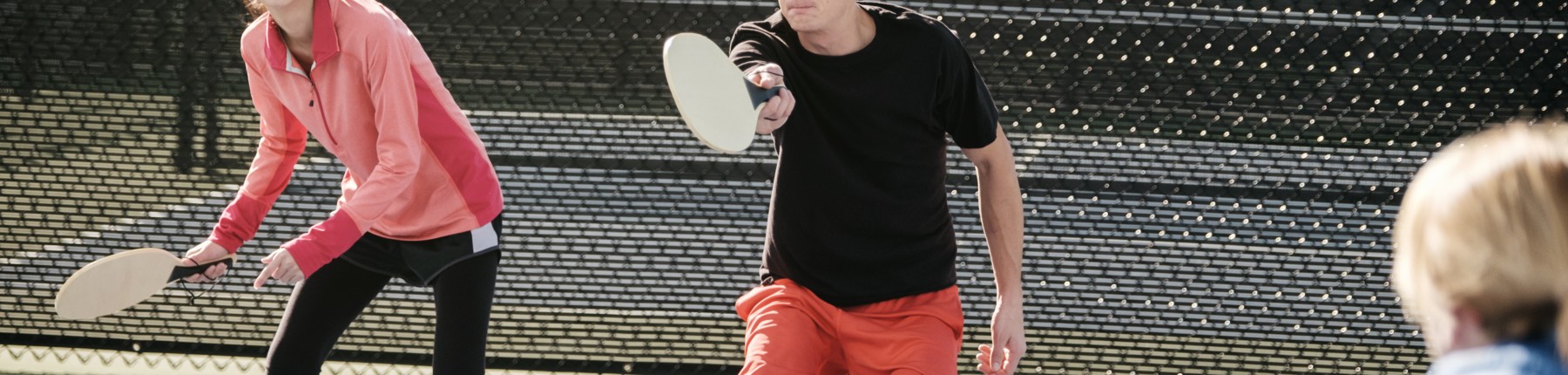 Couple playing pickleball outdoors on a court