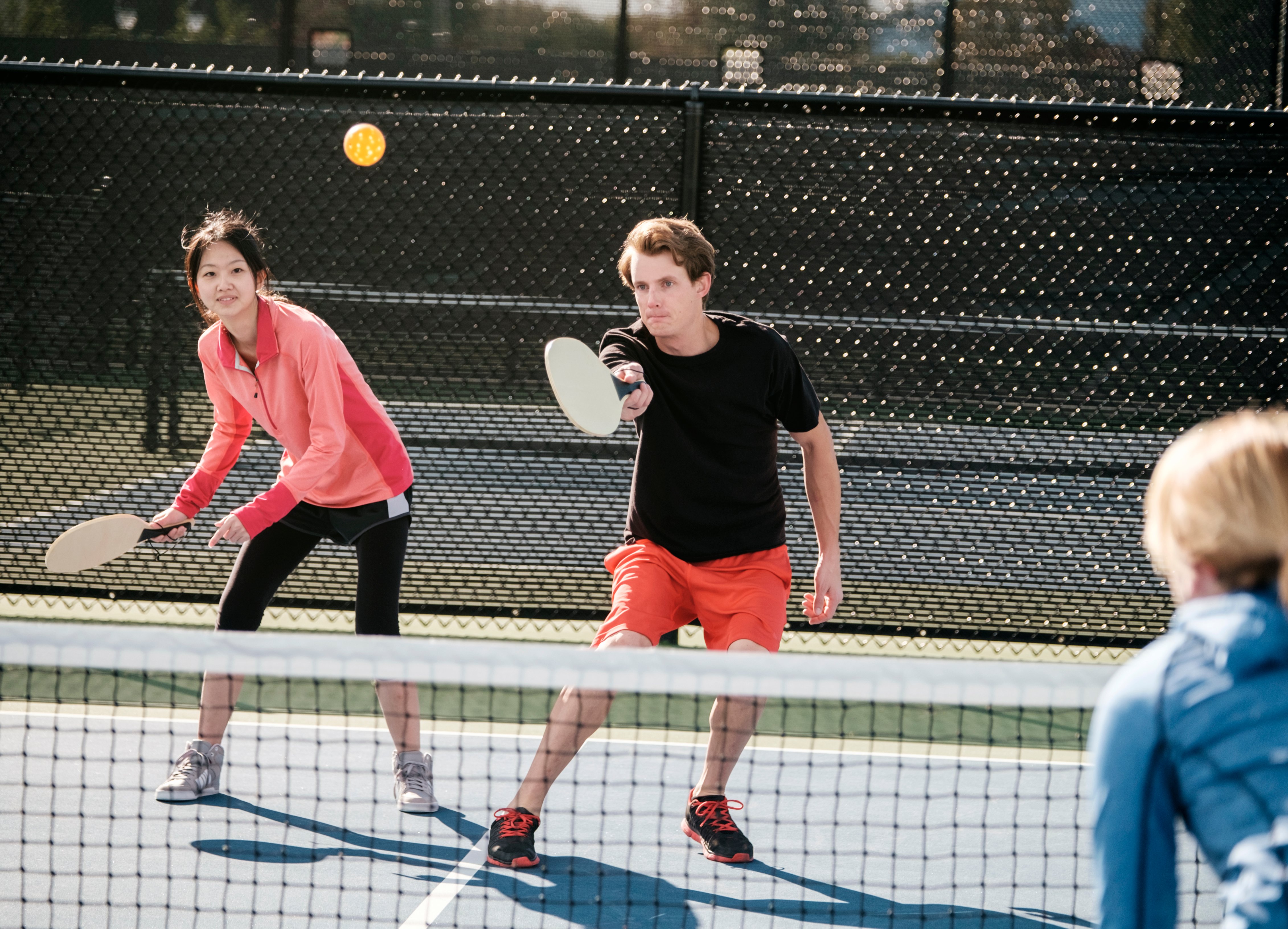 Couple playing pickleball outdoors on a court