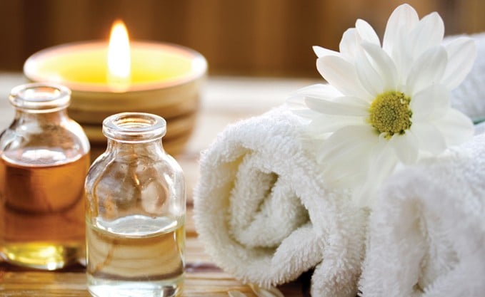 Rolled towels next to spa products set on a wooden table