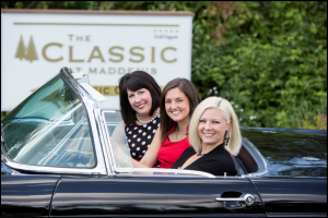 Three women in car next to sign for the Classic at Madden's on Gull Lake