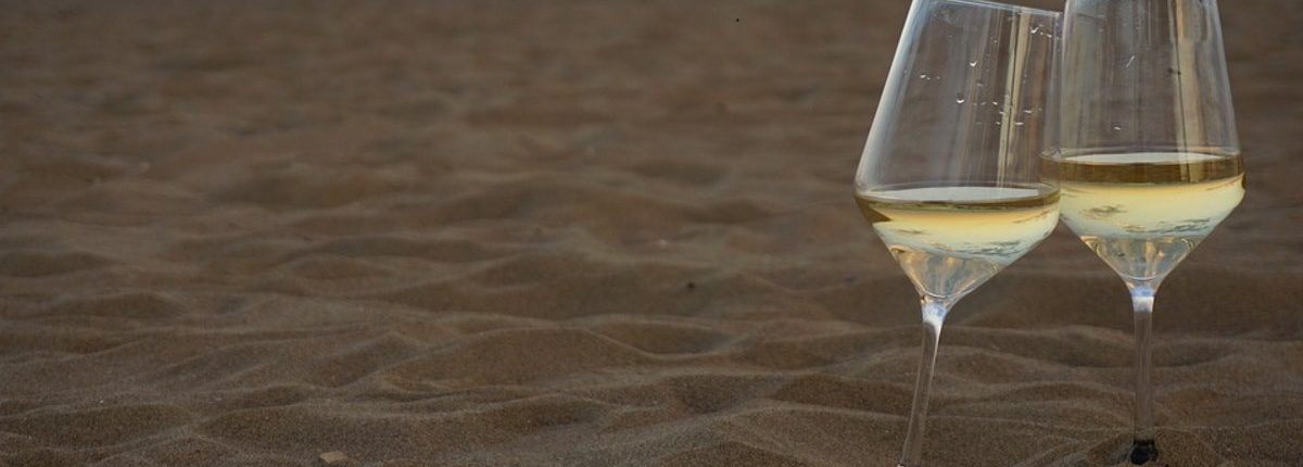 Crisp white wine in wine glass on a beautiful sand beach