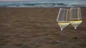 Crisp white wine in wine glass on a beautiful sand beach