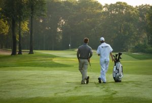 Golfer and his caddy at Maddens leaning on golf club admiring the Classic Golf course