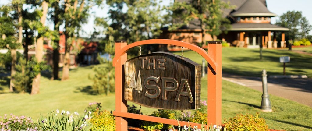 The Spa at Maddens sign in colorful garden on a sunny day.