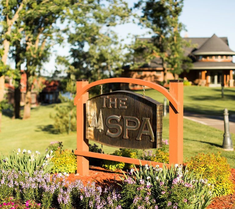 The Spa at Maddens sign in colorful garden on a sunny day.