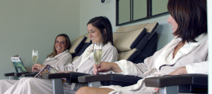 Woman in robes drinking champagne and receiving pedicures