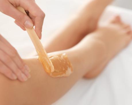 A hand applying wax to legs