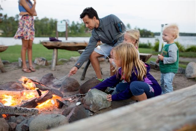 Family roasting marshmallows near a bonfire