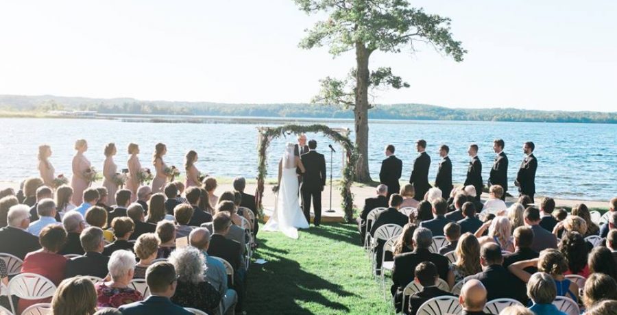 Rear view of the bride and groom at the aisle as seated guests look on.