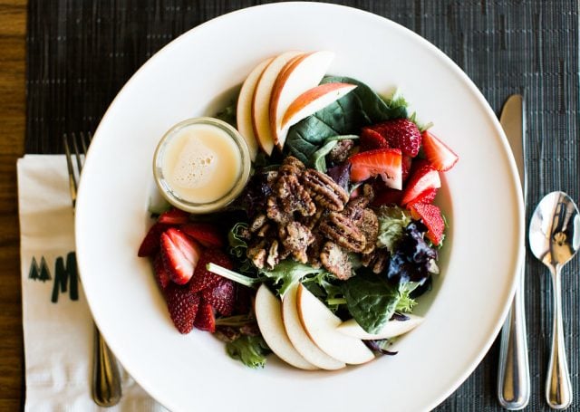 Spinach, strawberries, apple and walnut salad with dressing on a bowl