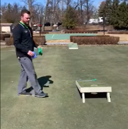 A man walking up to the cornhole game