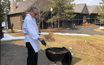 A man barbecuing pork outdoors