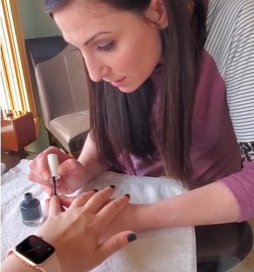 A beautician applying nail polish on the guests's nails