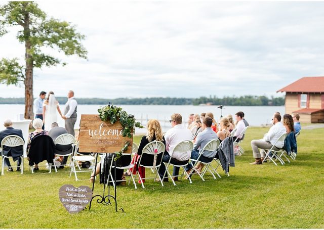 Seated guests looking at the bride and groom taking their vows next to the Gull Lake.