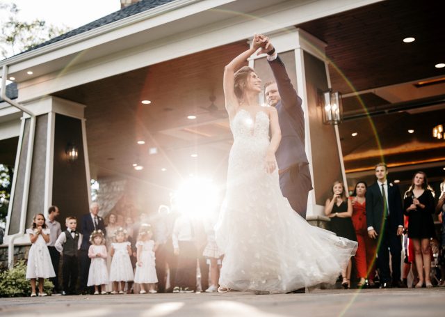 Bride and groom first dance as guests look on