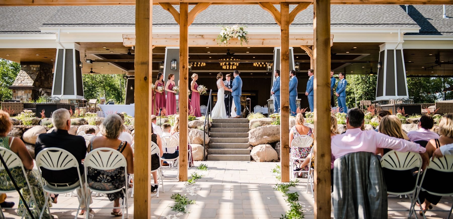 Seated guests looking at the bride and groom taking their vows next to the bridesmaids and groomsmen at The Pavilion