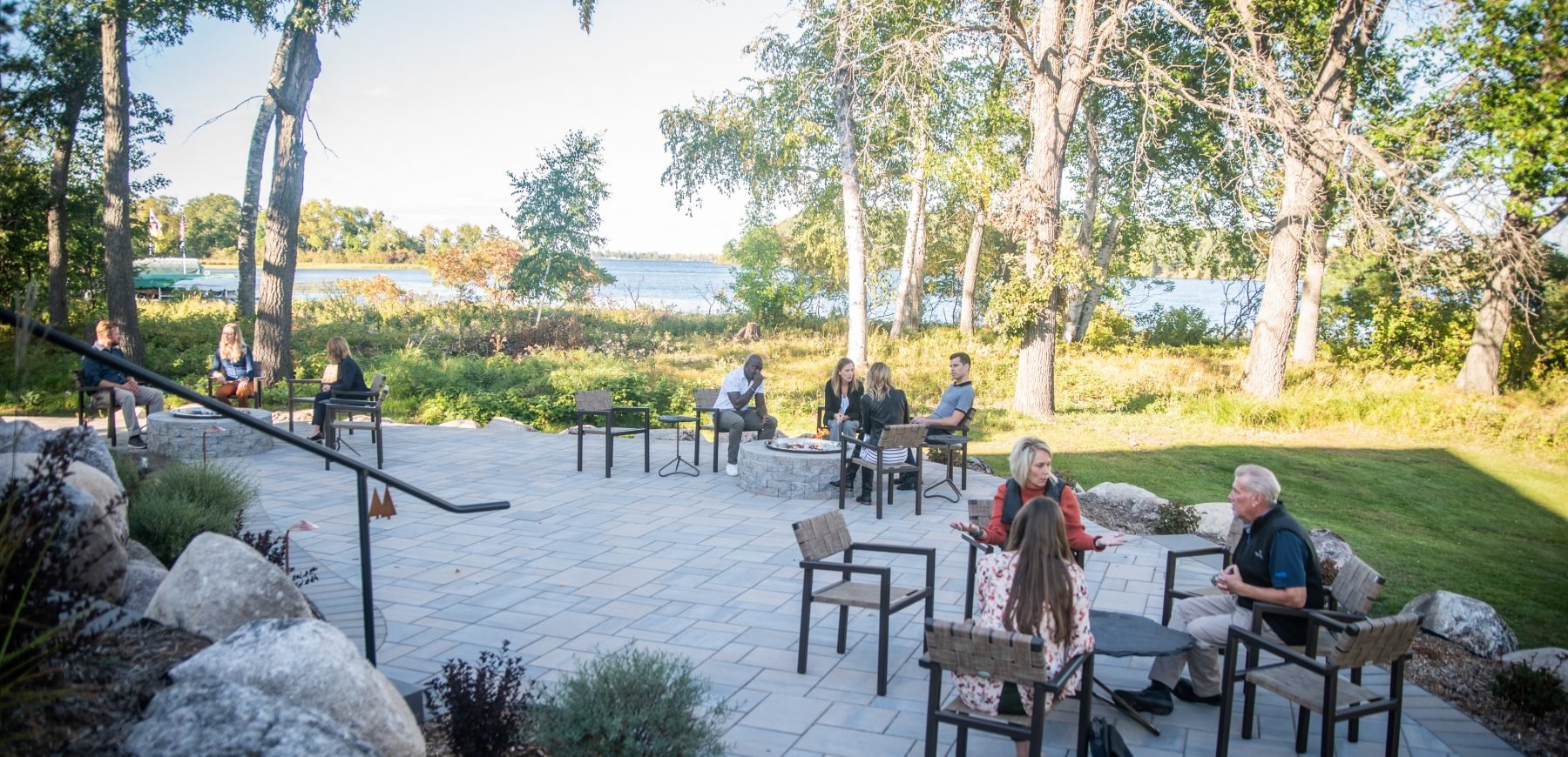 Guests sitting on the patio chairs next to the firepit at Madden's on Gull Lake.