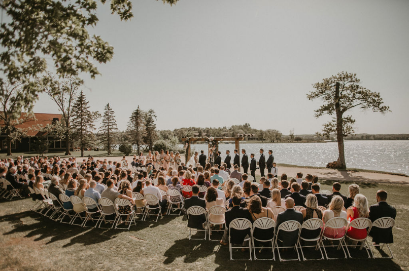 back shot of wedding guests sitting and watching the bride and groom at the aisle