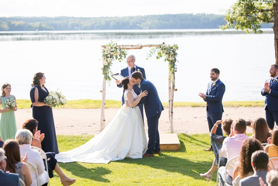 Bride and groom share a kiss as the guest cheer on