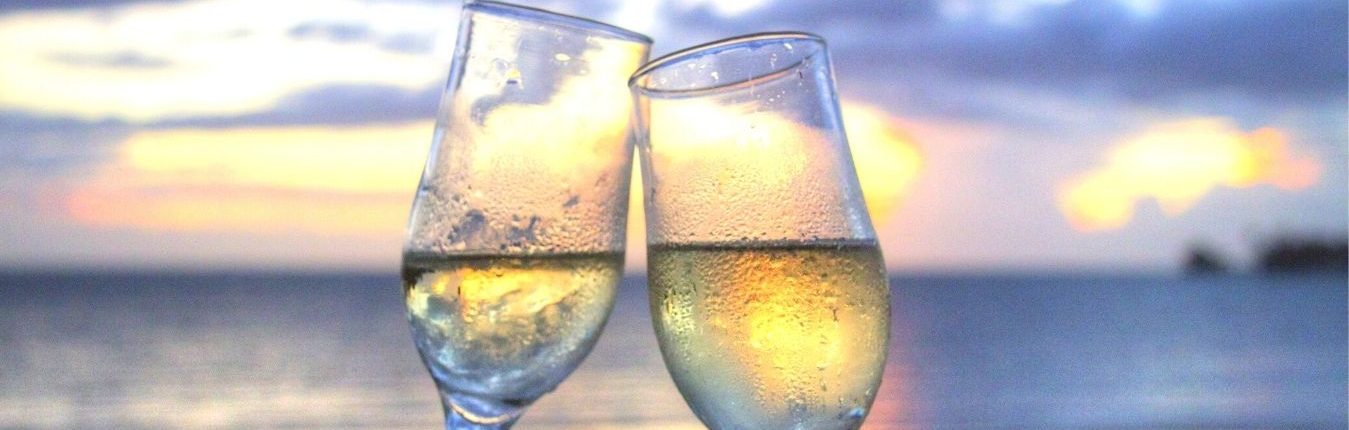 two champagne glasses clink by sunset
