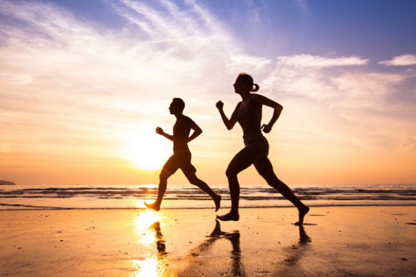 Two people run on the beach