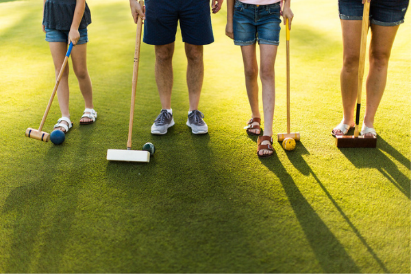 legs and feet of four people with croquet mallets