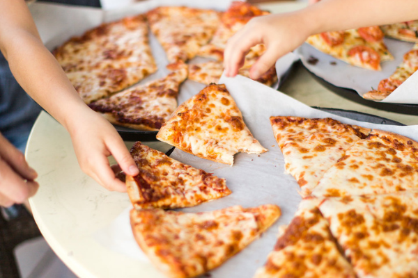 Hands reach in for multiple pizza slices