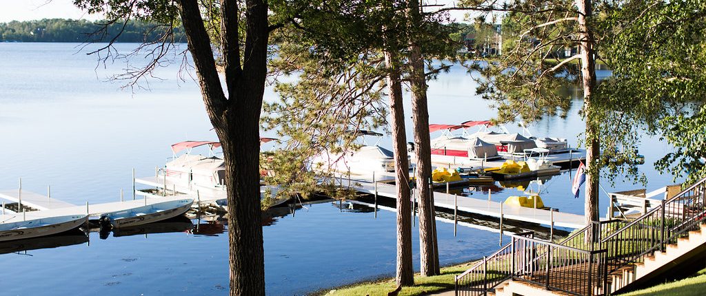 pontoon boats wait at dock on lake