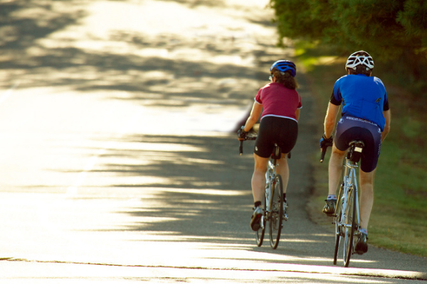 two people ride bikes on the road