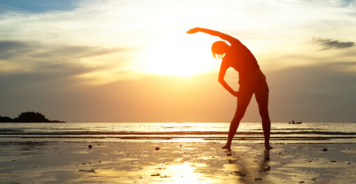 person stretches on the beach