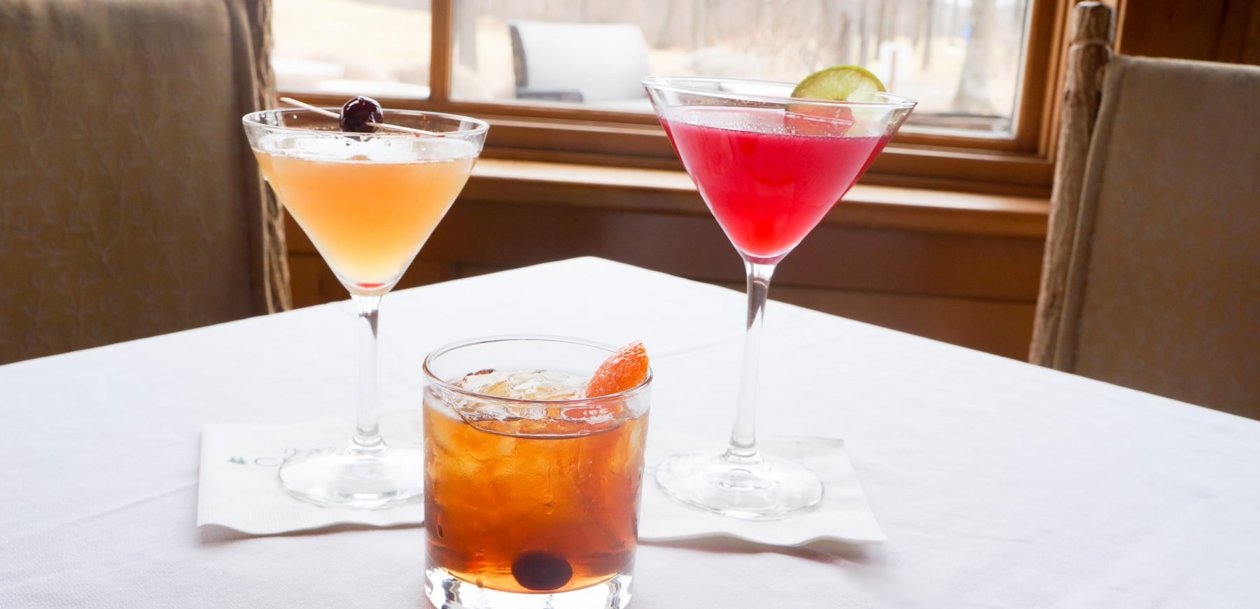 three cocktails on a while linen clothed table