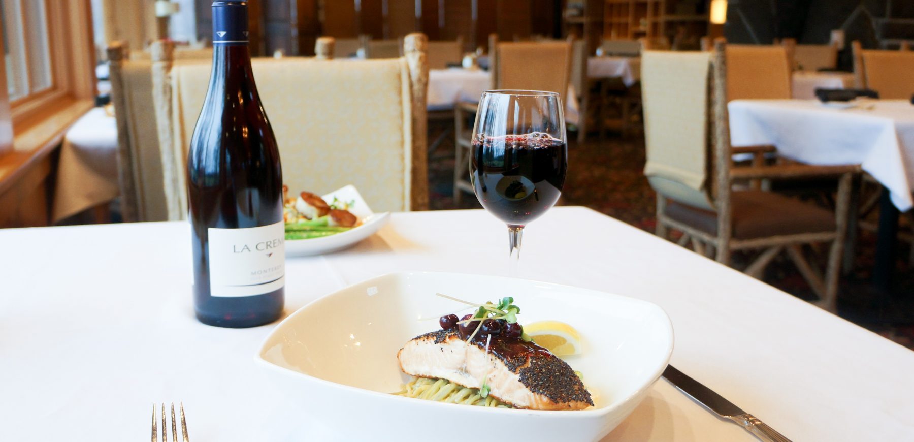 poppyseed salmon dish with glass of red wine