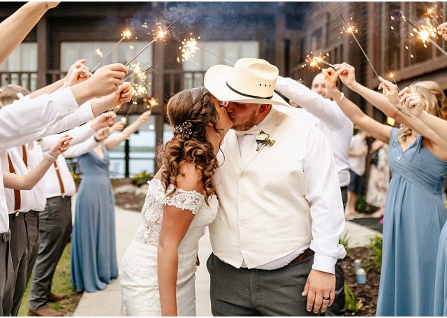 bride and groom kiss under sparklers held aloft