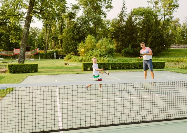 adult and child play tennis on a court