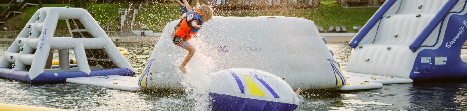 child jumps on inflatable slides in the lake