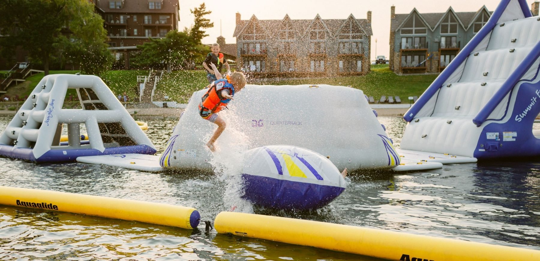 child jumps on inflatable slides in the lake