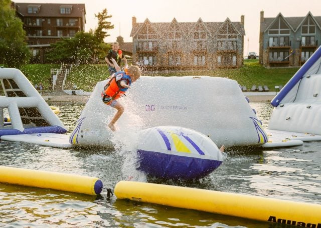 child jumps on inflatable slides in the lake