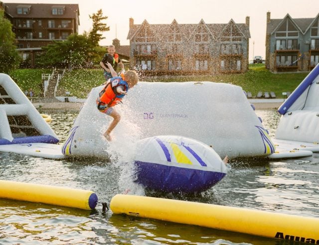 child jumps on inflatable slides in the lake