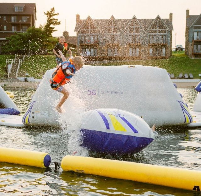 child jumps on inflatable slides in the lake